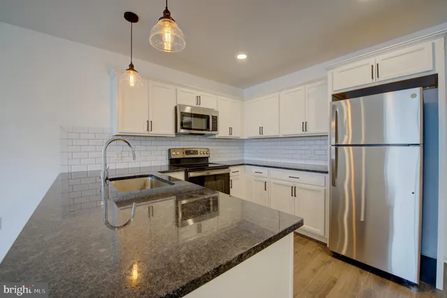 a kitchen with a refrigerator a microwave a sink and cabinets