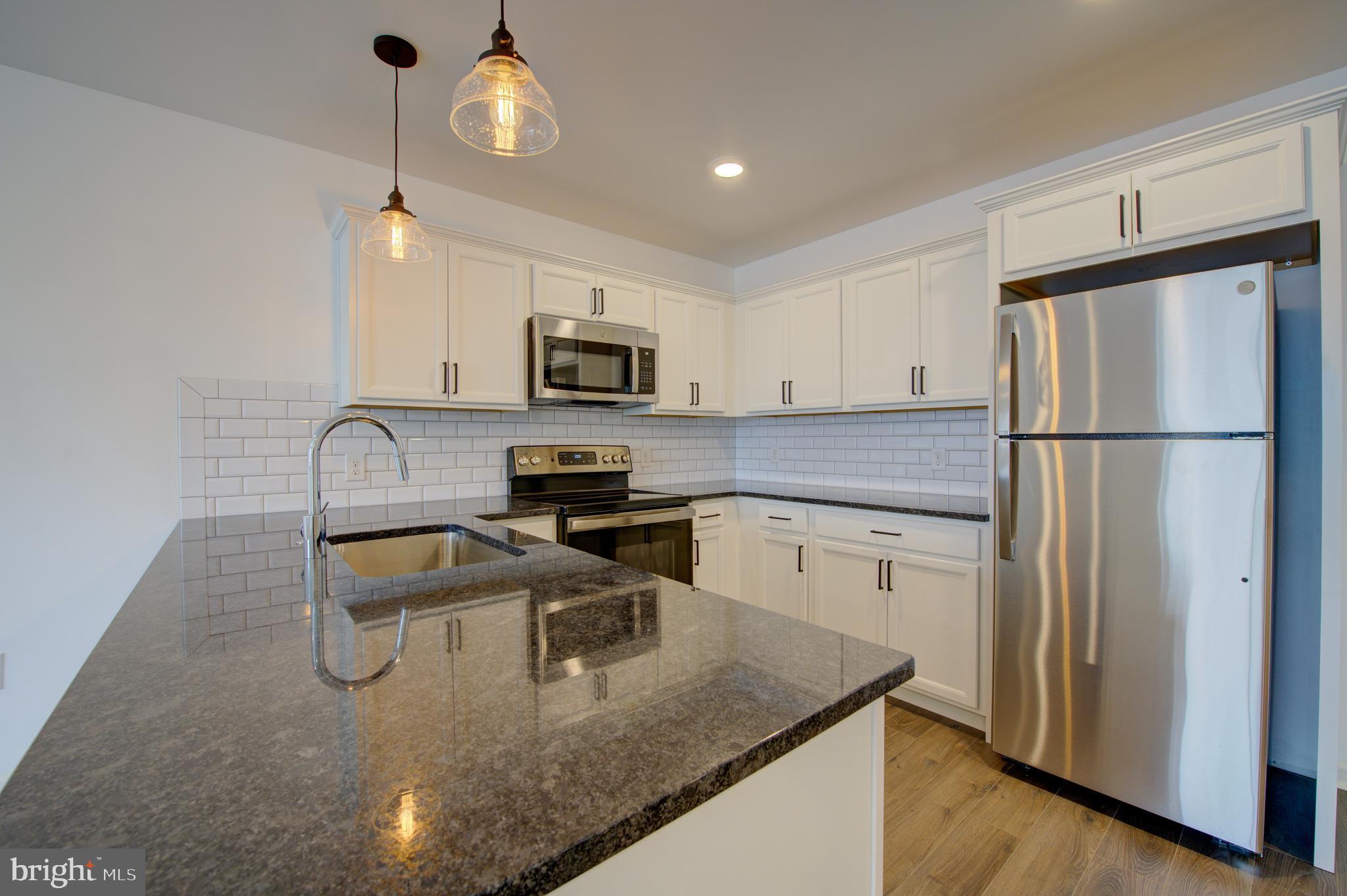 6649 Ridge Avenue, Unit B201 Philadelphia, PA 19128 - Photo 6 of 12 a kitchen with a refrigerator a microwave a sink and cabinets