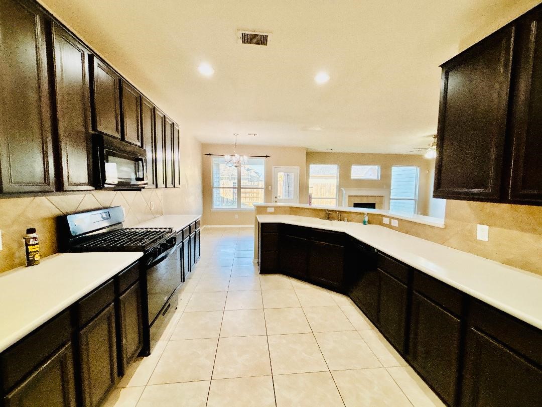 9947 Valance Way Conroe, TX 77385 - Photo 9 of 48 a large kitchen with stainless steel appliances kitchen island granite countertop a large counter top space a stove a sink and a refrigerator