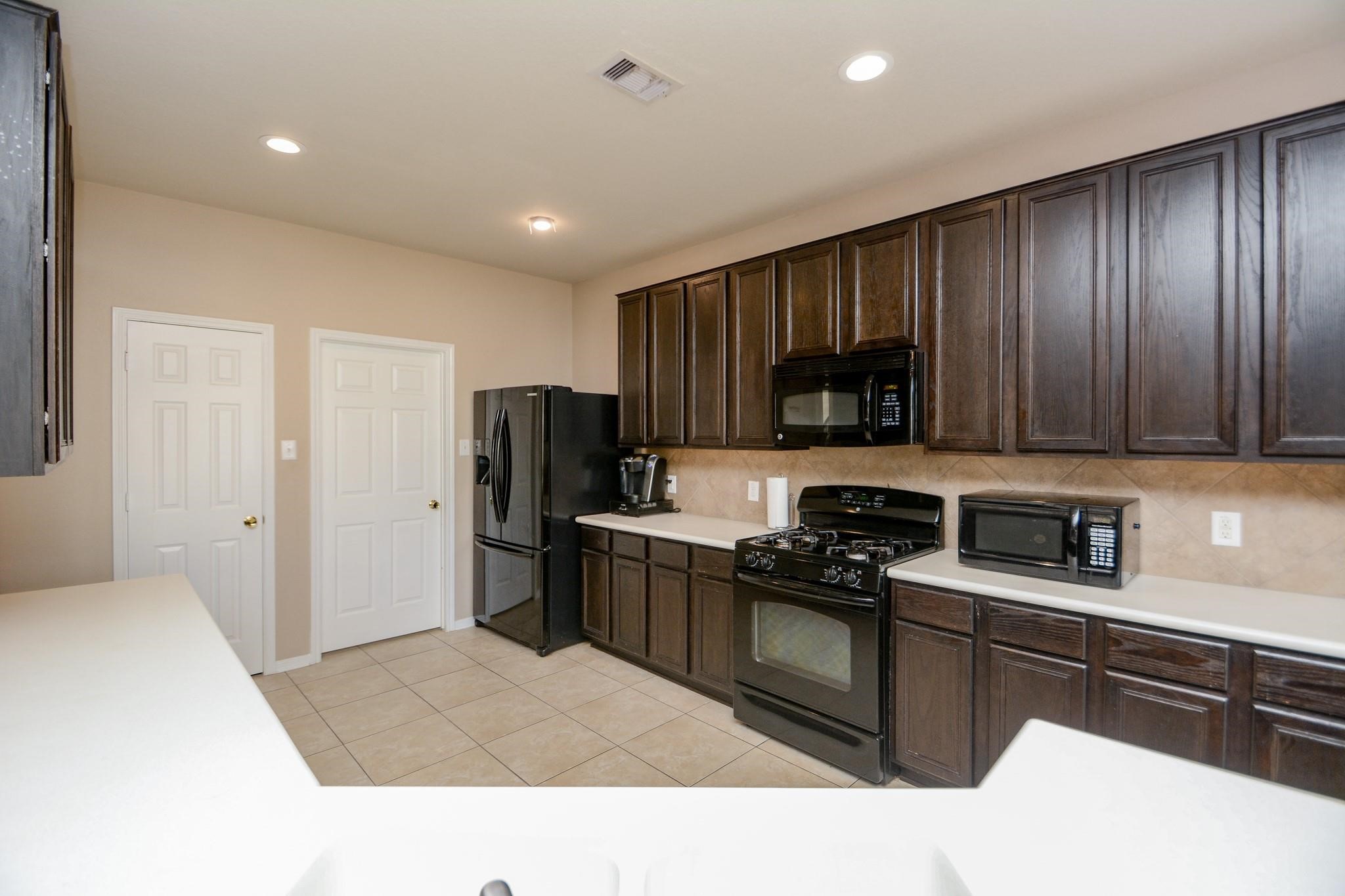 9947 Valance Way Conroe, TX 77385 - Photo 10 of 48 a kitchen with granite countertop stainless steel appliances a stove refrigerator and microwave