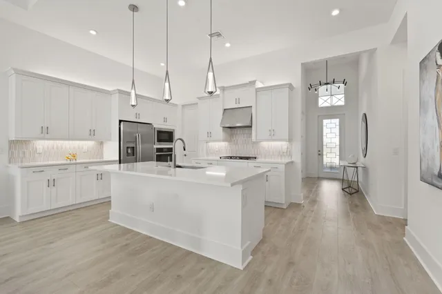 a large kitchen with white cabinets and stainless steel appliances