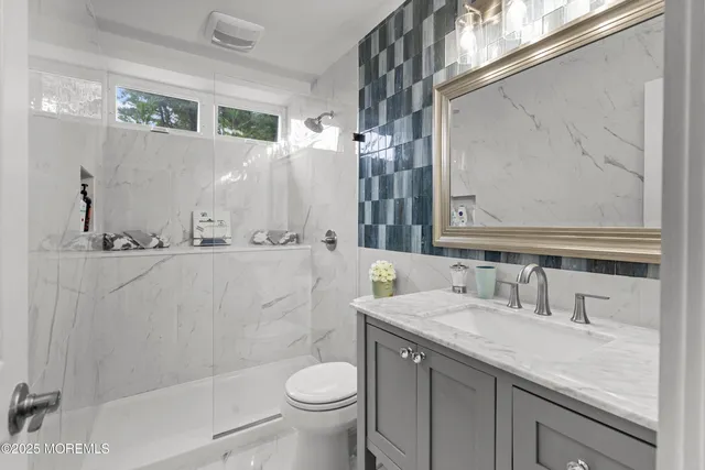 a bathroom with a granite countertop sink toilet and shower