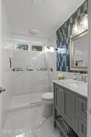 a bathroom with a granite countertop sink a mirror and a toilet