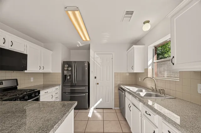 a kitchen with stainless steel appliances white cabinets and a stove top oven