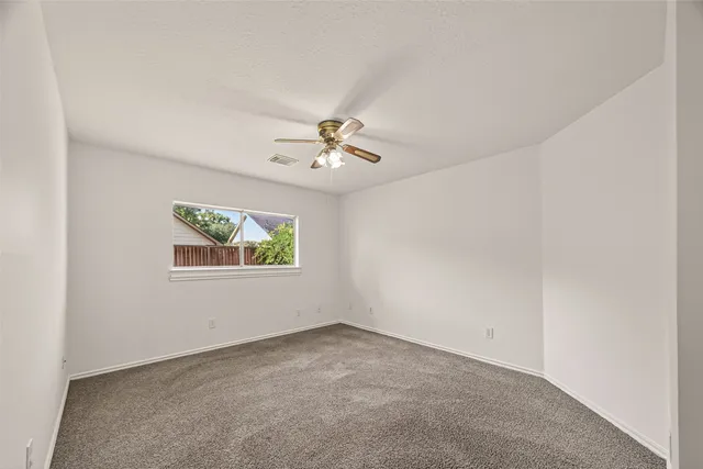 an empty room with a chandelier fan and windows