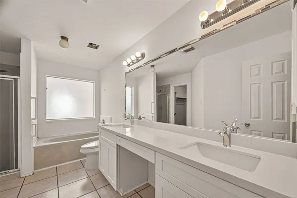 a bathroom with a granite countertop bathtub shower sink vanity and toilet