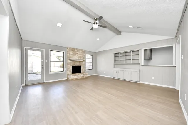 an empty room with windows and fireplace