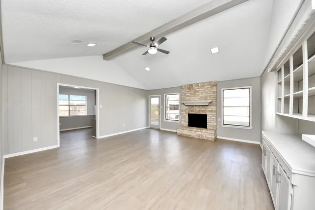 an empty room with windows and a fireplace