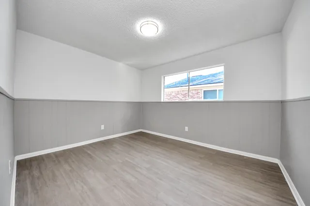a view of an empty room with wooden floor and window
