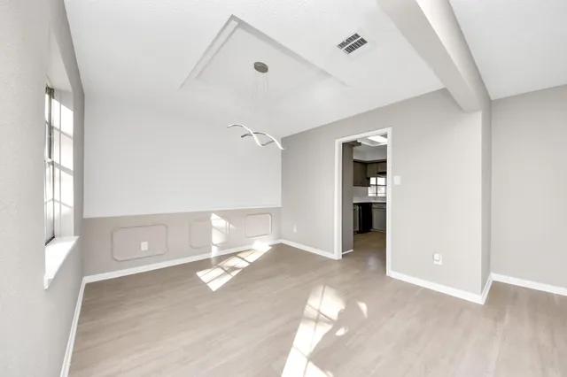 a view of empty room with wooden floor and kitchen