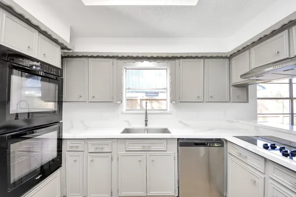 a kitchen with granite countertop a sink cabinets stainless steel appliances and a window