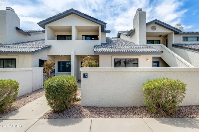 a view of a white house with potted plants and a table and chairs