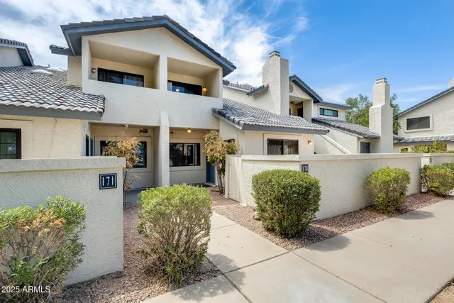 a view of a white house next to a yard with big trees