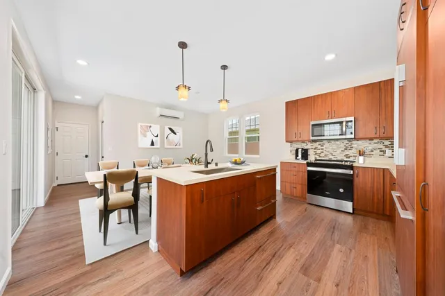 a large kitchen with stainless steel appliances granite countertop a stove and a wooden floors