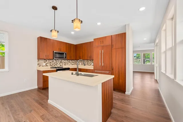 a kitchen with stainless steel appliances granite countertop a sink a stove and a wooden floors