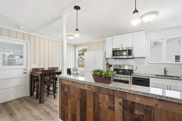 a kitchen with a refrigerator a stove top oven a sink dishwasher and white cabinets with wooden floor