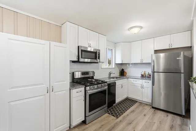 a kitchen with stainless steel appliances granite countertop a stove a refrigerator a sink a dining table and chairs with wooden floor