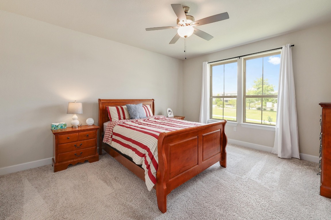 8312 Corrigan Pass Austin, TX 78744 - Photo 14 of 27 a spacious bedroom with a bed and a chandelier