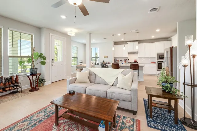 a living room with furniture kitchen view and a large window