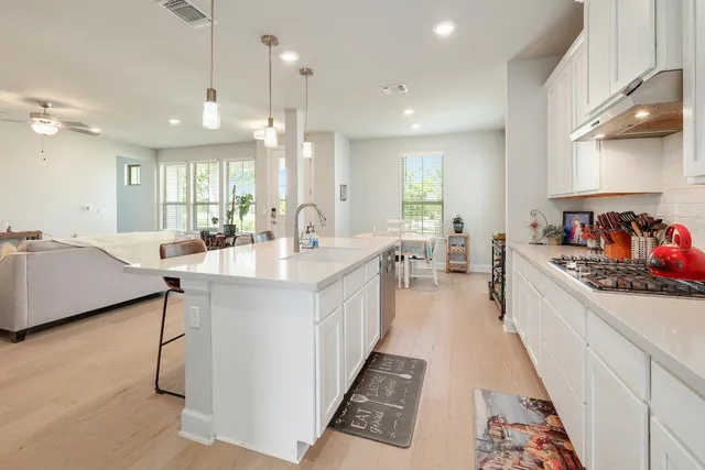 a large white kitchen with a large counter top appliances and cabinets