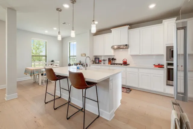 a kitchen with stainless steel appliances granite countertop a sink a stove a refrigerator and island with wooden floor