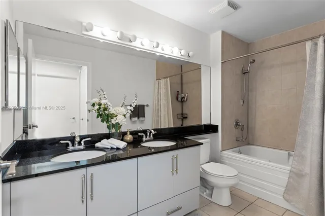 a bathroom with a granite countertop sink toilet a large mirror a shower and a bathtub