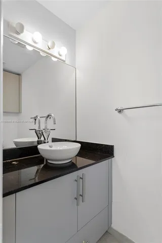 a bathroom with a granite countertop sink and a mirror