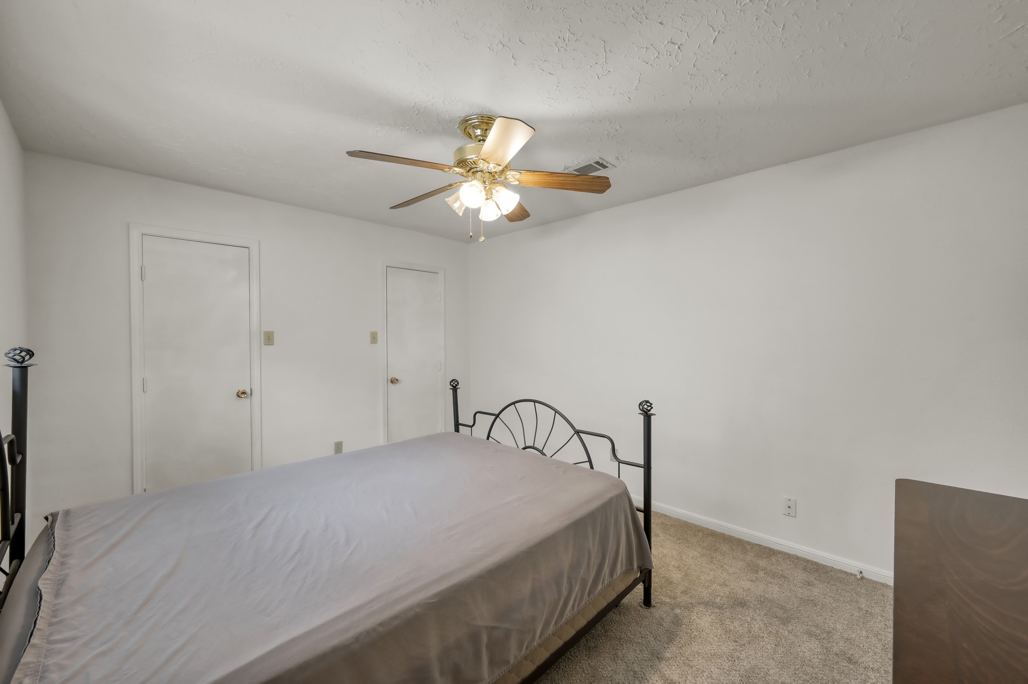 4314 Enchantedgate Drive Spring, TX 77373 - Photo 35 of 47 Guest bedroom features neutral walls and carpeting, a ceiling fan with light, and two doors, offering a simple and cozy space.