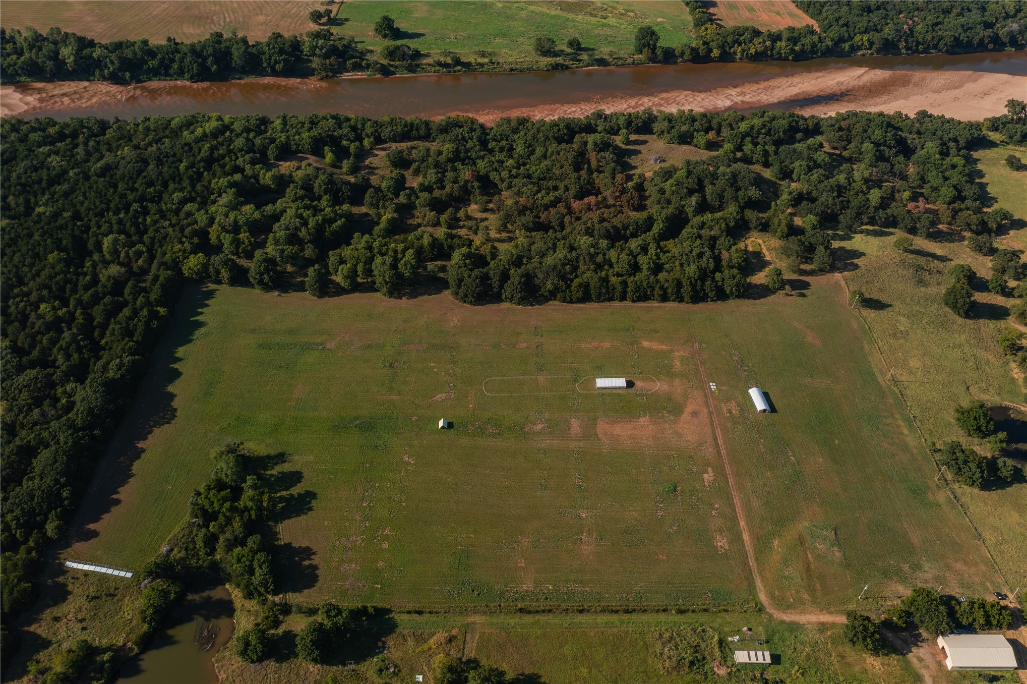 0 West Dunkin Road Cushing, OK 74023 - Photo 6 of 62 Expansive acreage featuring a substantial field, dense tree lines, and a visible body of water