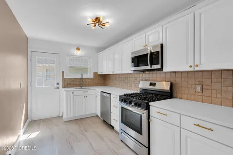 a kitchen with granite countertop a sink a stove a microwave and cabinets