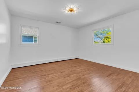 a view of an empty room with window and wooden floor