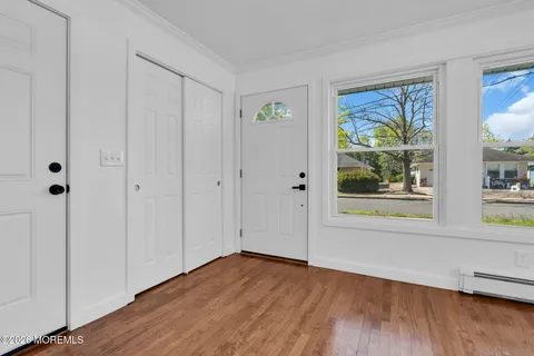 a view of an empty room with window and wooden floor