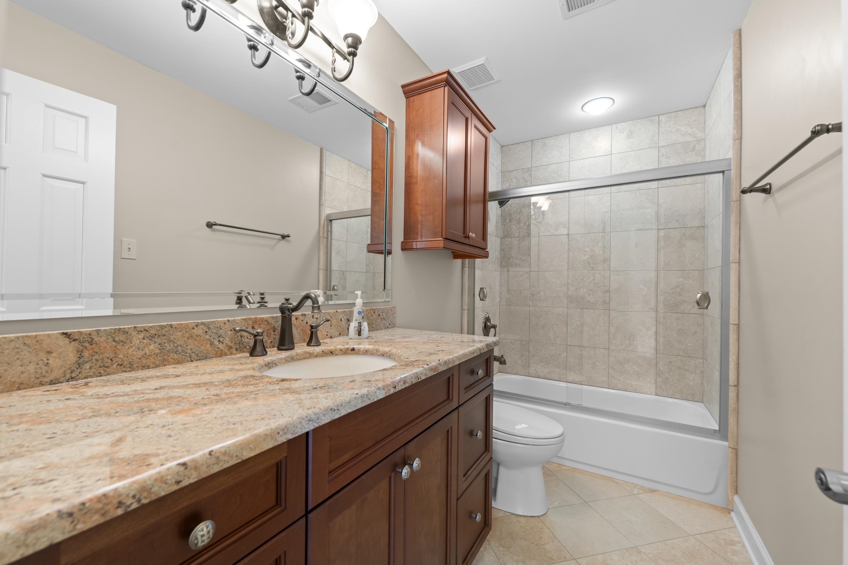 677 Gunnison Cove Collierville, TN 38017 - Photo 18 of 30 a bathroom with a granite countertop sink a toilet a mirror and shower