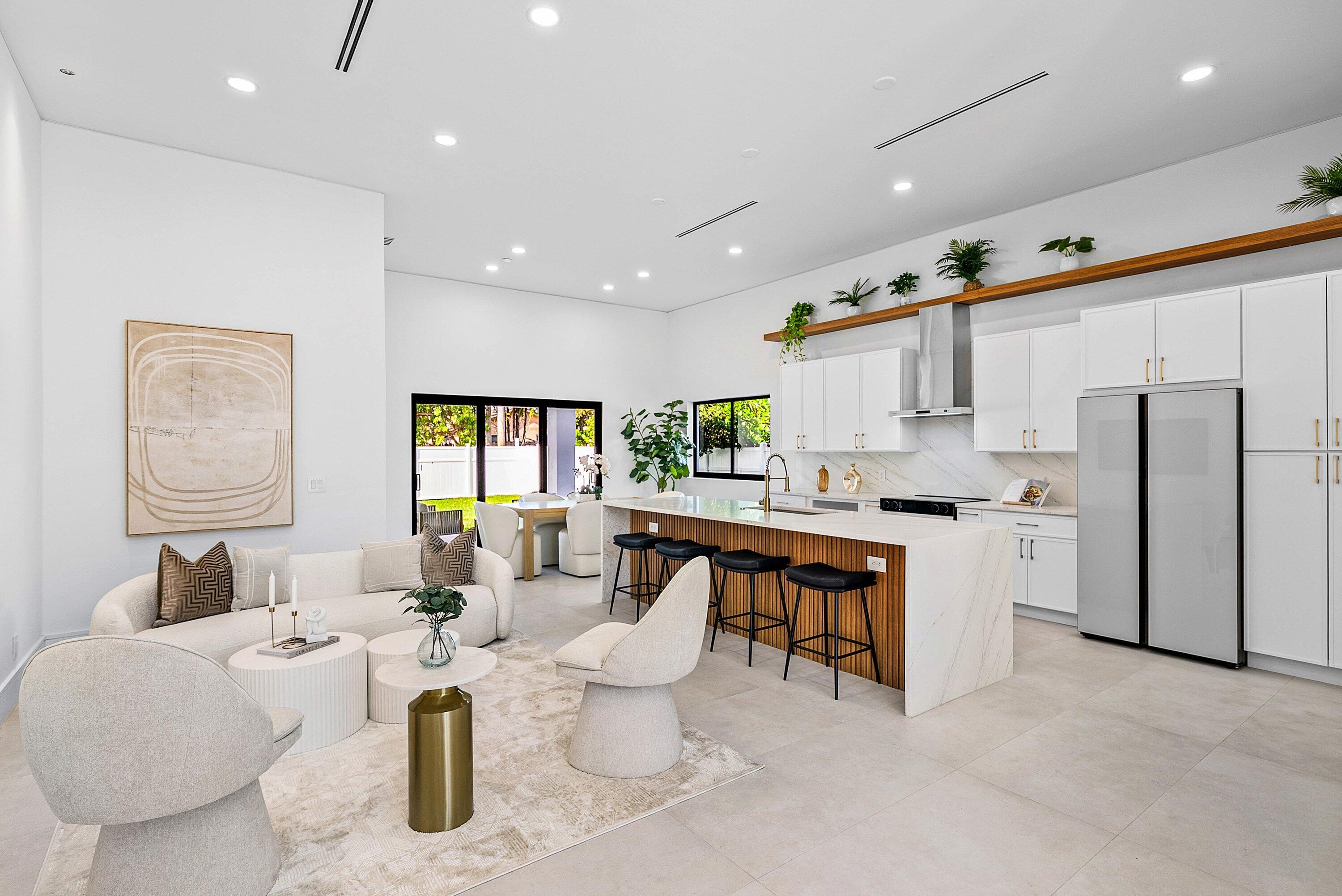 3361 Northeast 4th Avenue Boca Raton, FL 33431 - Photo 43 of 44 a large white kitchen with stainless steel appliances kitchen island granite countertop a refrigerator a sink dishwasher a dining table and chairs with wooden floor