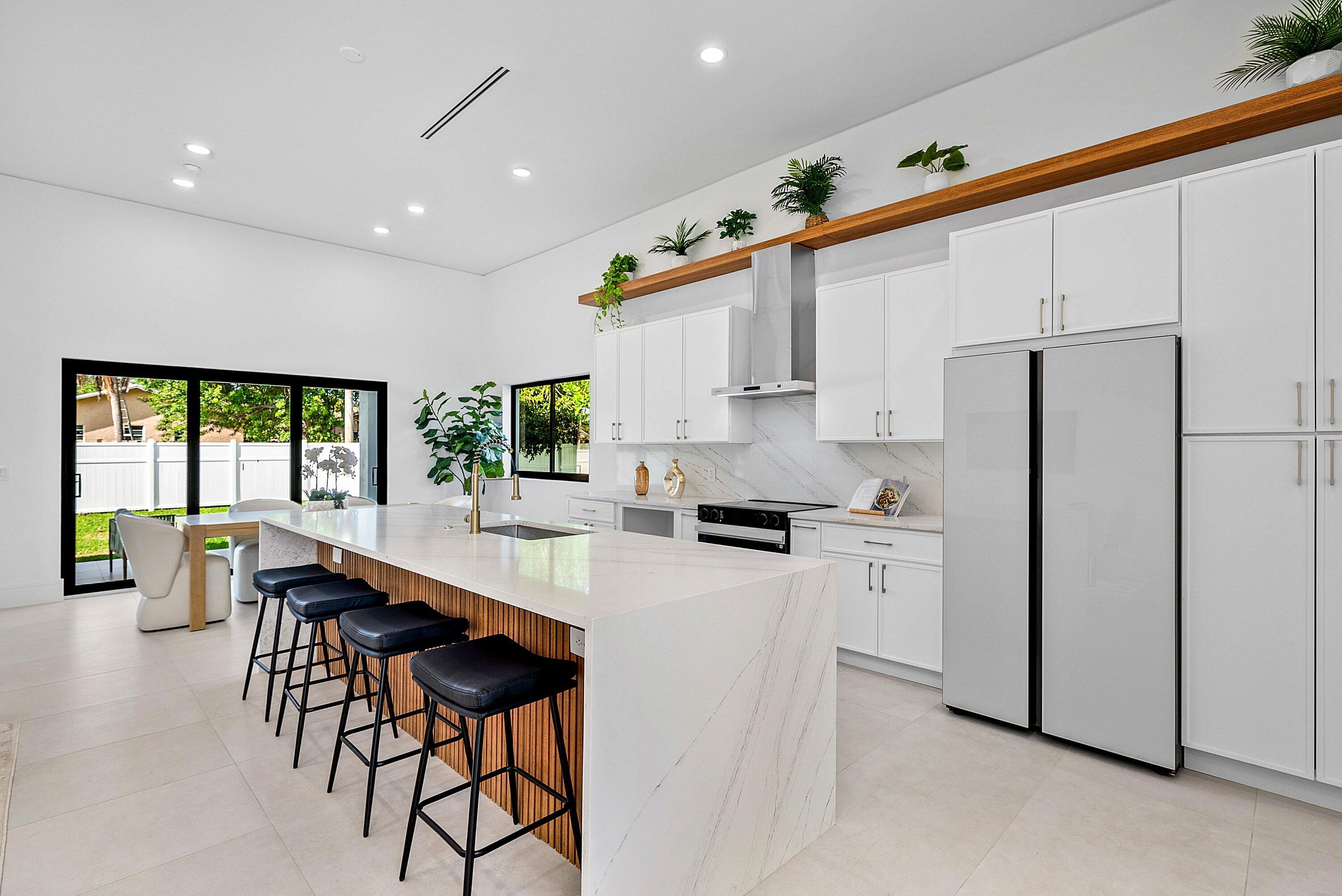 3361 Northeast 4th Avenue Boca Raton, FL 33431 - Photo 13 of 44 a kitchen with stainless steel appliances kitchen island wooden floors and white cabinets