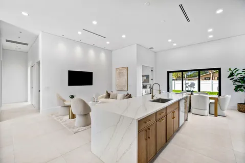 a living room with stainless steel appliances furniture a rug and a kitchen view