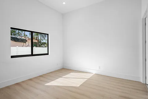 an empty room with wooden floor and window