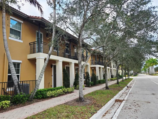 a view of a white house with a large tree