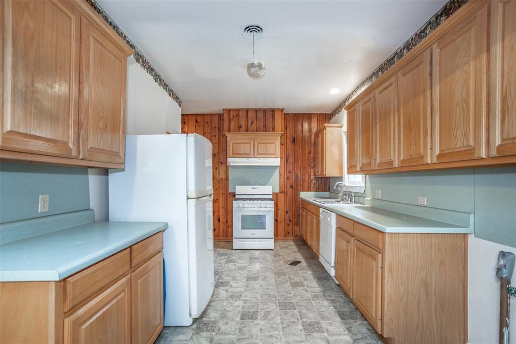 206 Ritchey Street Gainesville, TX 76240 - Photo 12 of 36 a kitchen with stainless steel appliances granite countertop a refrigerator a sink dishwasher and wooden cabinets with wooden floor