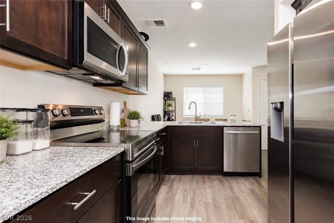 12369 Golden Wreath Road, Unit 2 Las Vegas, NV 89183 - Photo 3 of 19 A well-appointed kitchen features dark wood cabinetry, light granite countertops, and modern stainless steel appliances.