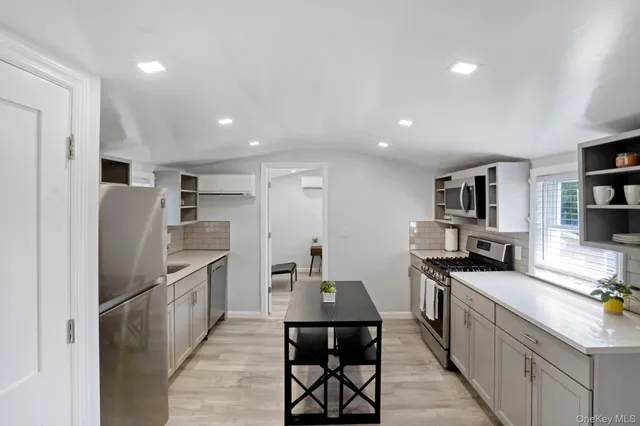 a kitchen with stainless steel appliances granite countertop a refrigerator a stove a sink a dining table and chairs