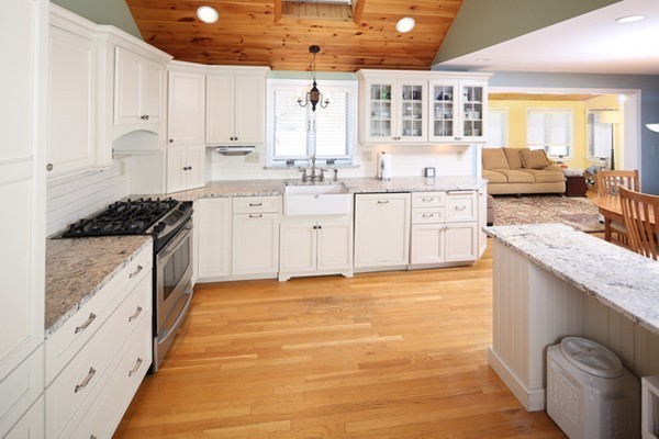 a kitchen with stainless steel appliances kitchen island granite countertop a stove a sink and white cabinets