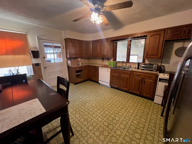 a kitchen with stainless steel appliances granite countertop a sink dishwasher stove a refrigerator with a dining table and chairs with wooden floor