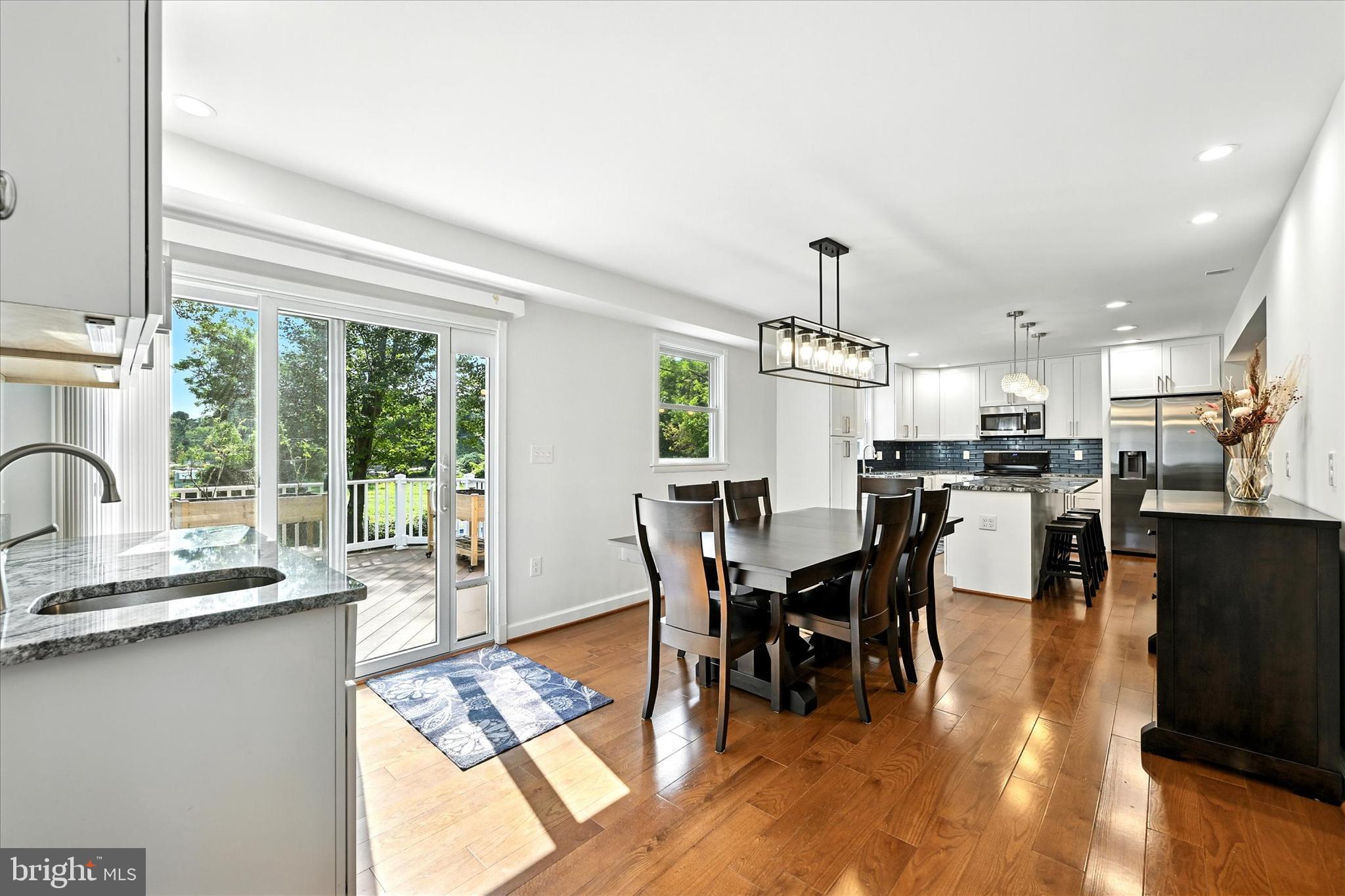 3111 Northwind Road Baltimore, MD 21234 - Photo 16 of 81 a kitchen with stainless steel appliances granite countertop a stove a refrigerator a sink a dining table and chairs with wooden floor