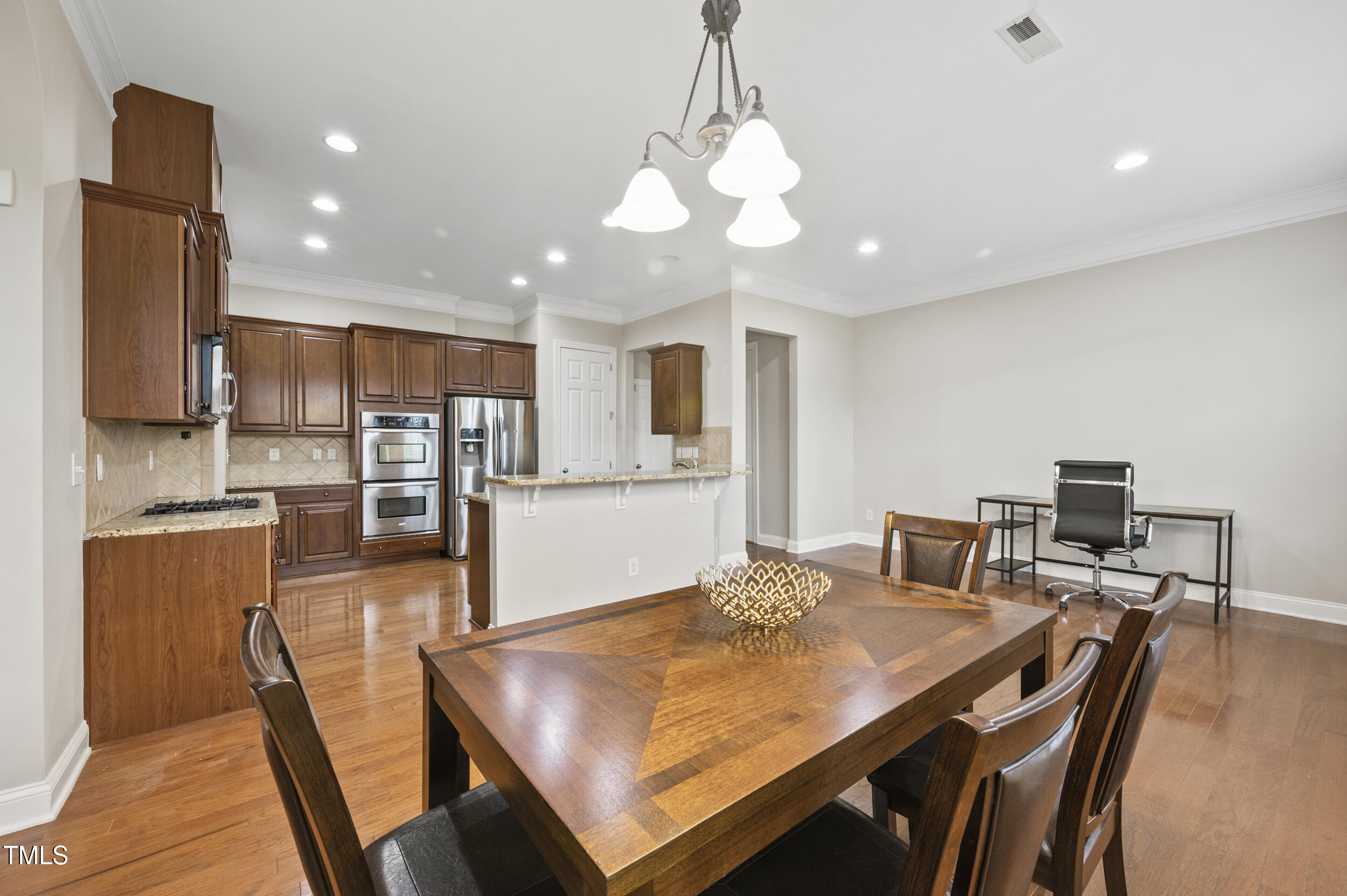 1204 Chapanoke Road Raleigh, NC 27603 - Photo 14 of 45 a kitchen with stainless steel appliances granite countertop a stove refrigerator a dining table and chairs with wooden floor