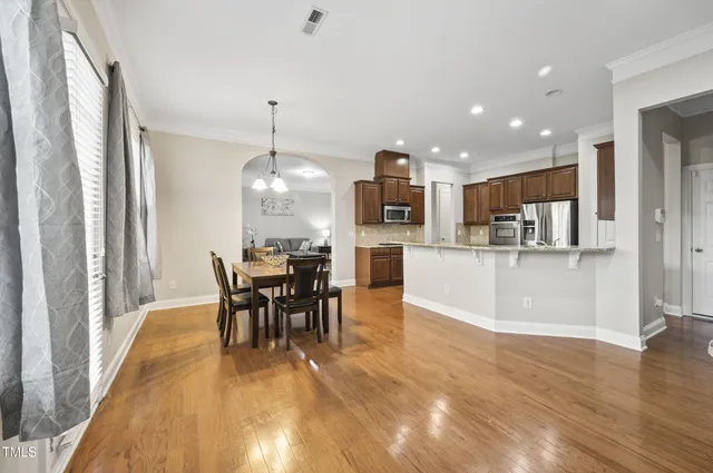 a kitchen with stainless steel appliances granite countertop a stove refrigerator a dining table and chairs with wooden floor