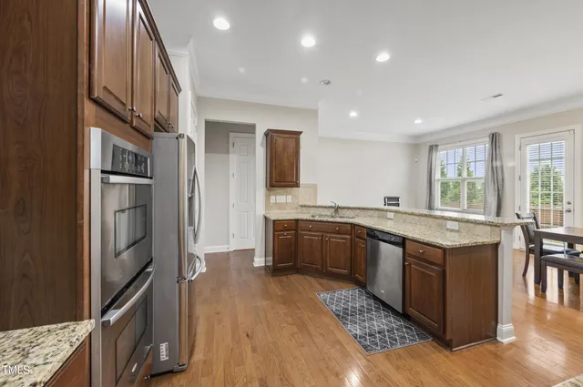 a kitchen with stainless steel appliances granite countertop a refrigerator a stove and a sink