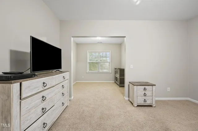 a living room with flat screen tv on dresser and a flat screen tv