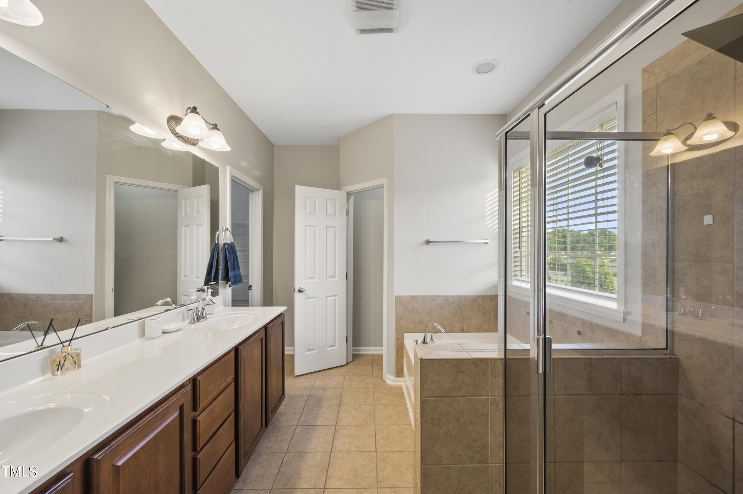 1204 Chapanoke Road Raleigh, NC 27603 - Photo 37 of 45 a bathroom with a double vanity sink a large mirror and a shower