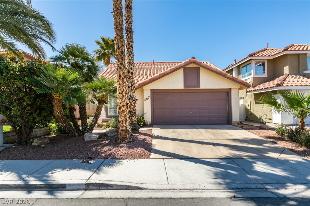 307 Cavalla Street Henderson, NV 89074 - Photo 1 of 44 Mature palm trees adorn this residence with a terracotta-tiled roof and an integrated garage.